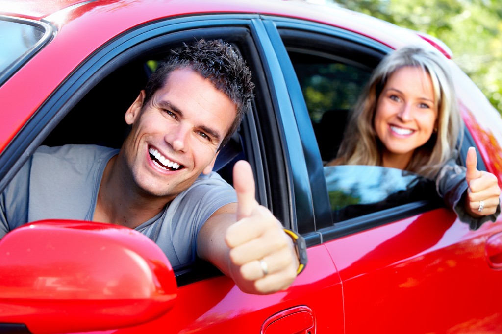 Happy couple in red car - save 15% off auto maintenance services in Desborough, Northamptonshire at Carrs Automotive